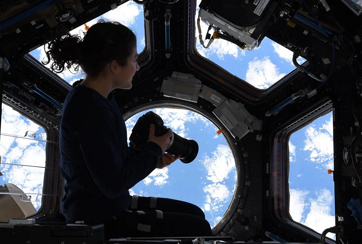 an astronaut besides the window on international space station
