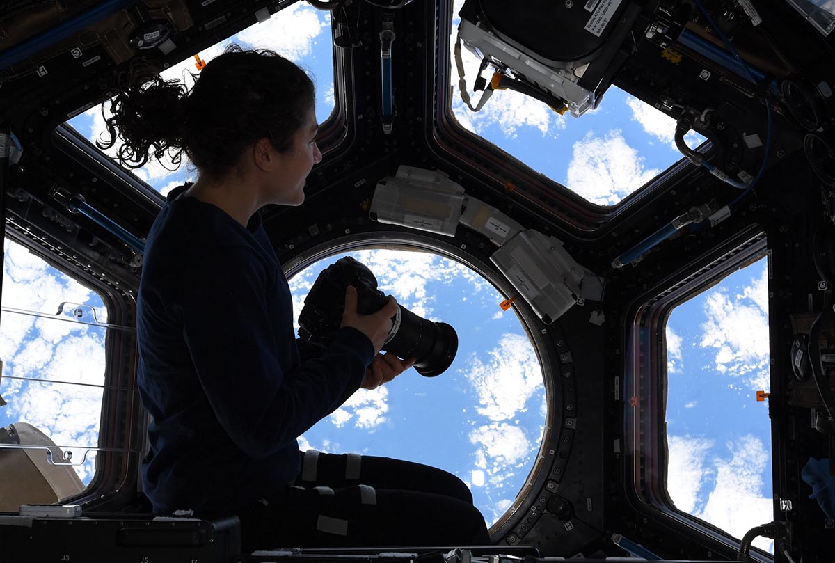 an astronaut besides the window on international space station